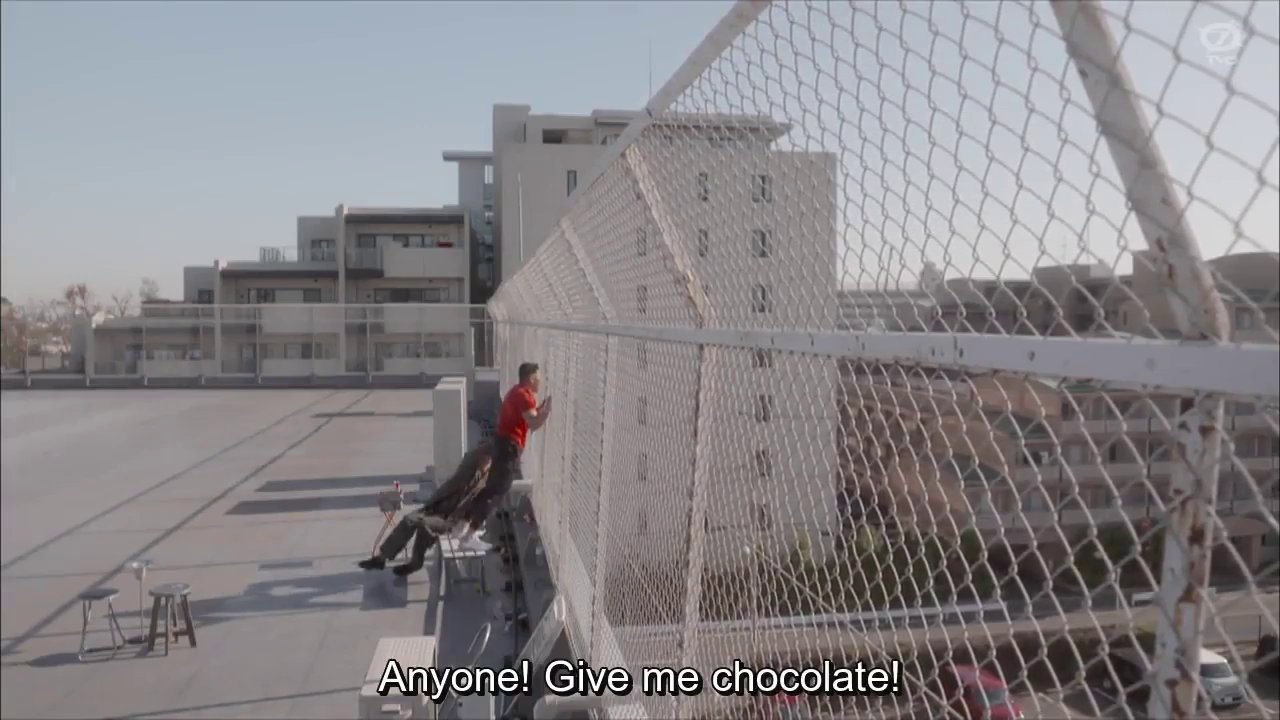 Masaru and Matsuda on the roof bench, Masaru shouting through the fence: Anyone!  Give me chocolate!