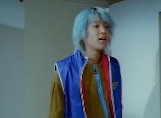 Shion, hair bluer than before, wearing a royal blue vest with the sleeves zipped off.